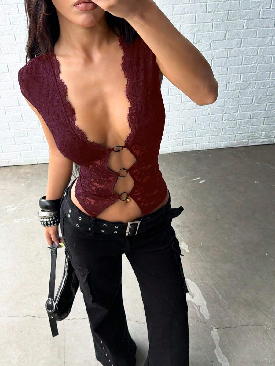 Women's black slim fit semi-sheer blouse featuring contrast lace detailing, a deep V hollow design with ring accent, asymmetrical hem, and cap sleeves.
