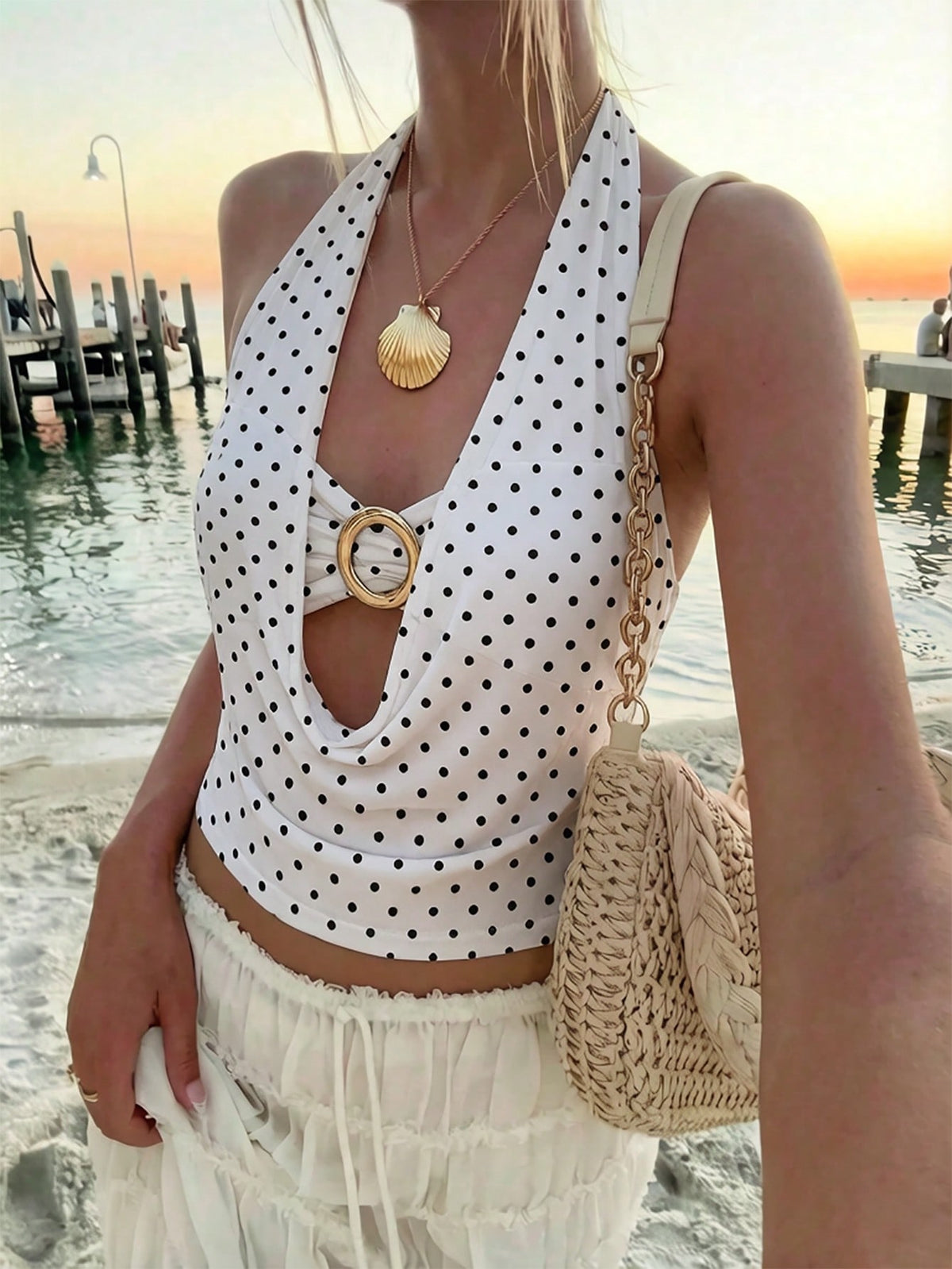Brown and white polka dot semi-sheer halter camisole top with a plunging neckline, backless design, draped front, and metallic studded embellishments.