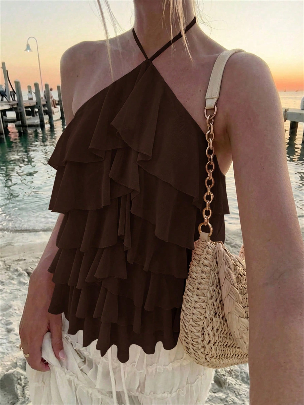 Women's sleeveless halter neck top featuring tiered ruffle layers, a backless cut, and an asymmetrical hem.