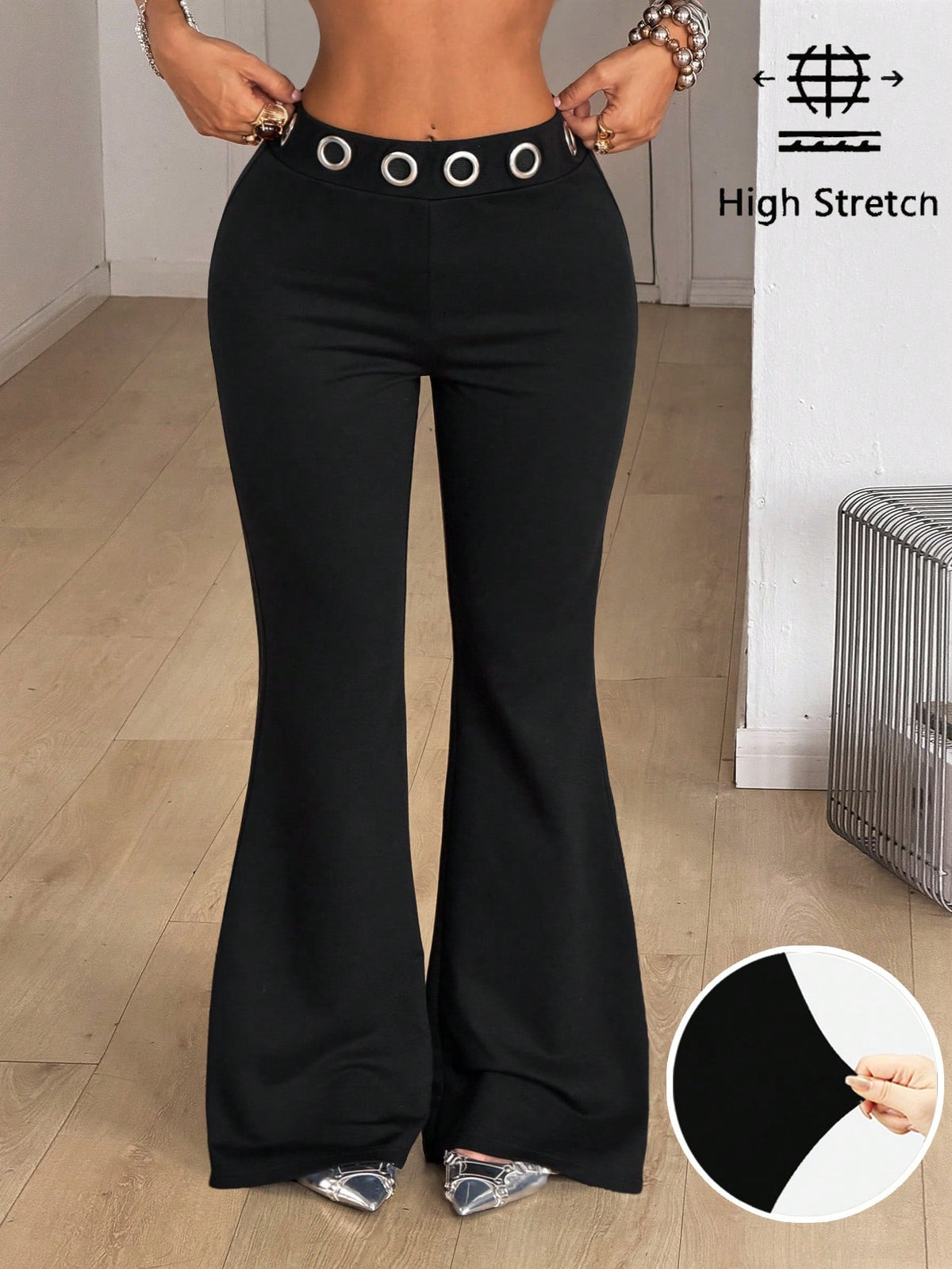 Women's black stretchy mid rise flare pants with grommet eyelet detailing along the legs.