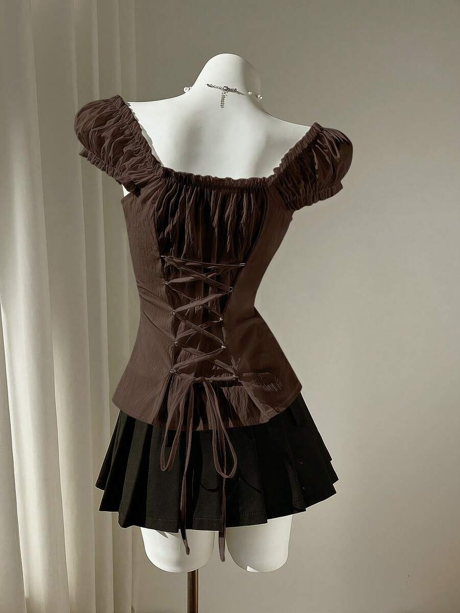 Women's black off-shoulder cap sleeve blouse with ruffled detailing and a tie-back design.