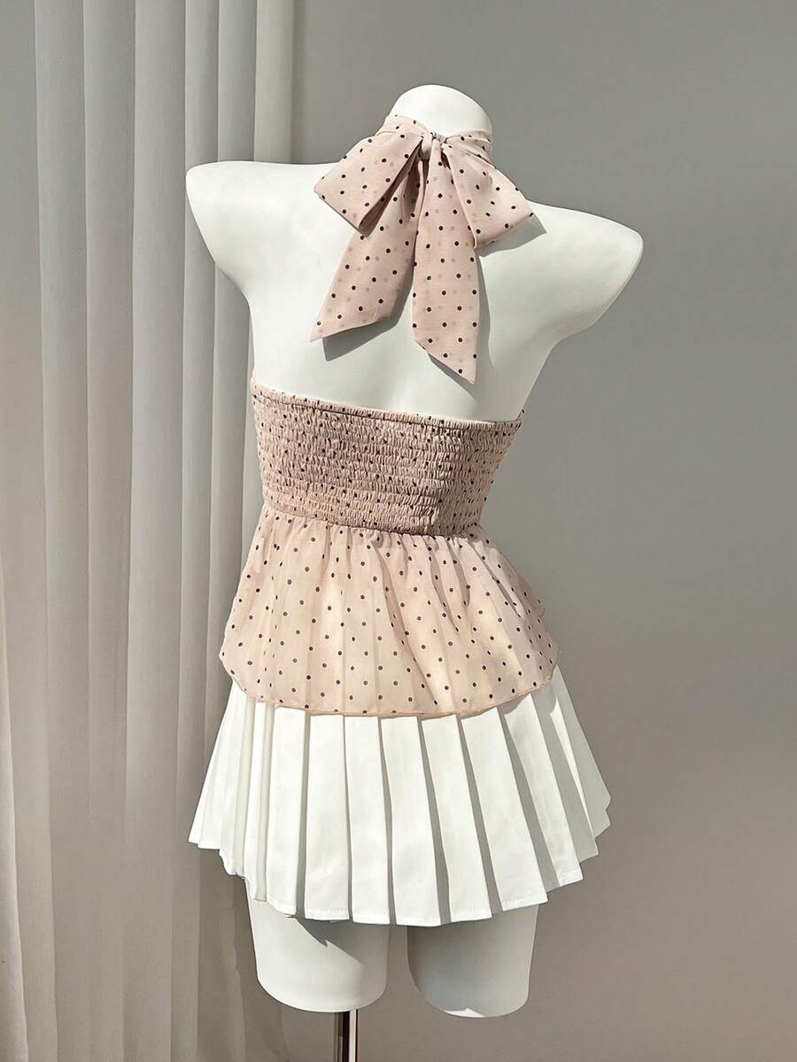 Women's white sleeveless halter neck top featuring pleated fabric, backless tie strap design, and a flared layered ruffle hem.