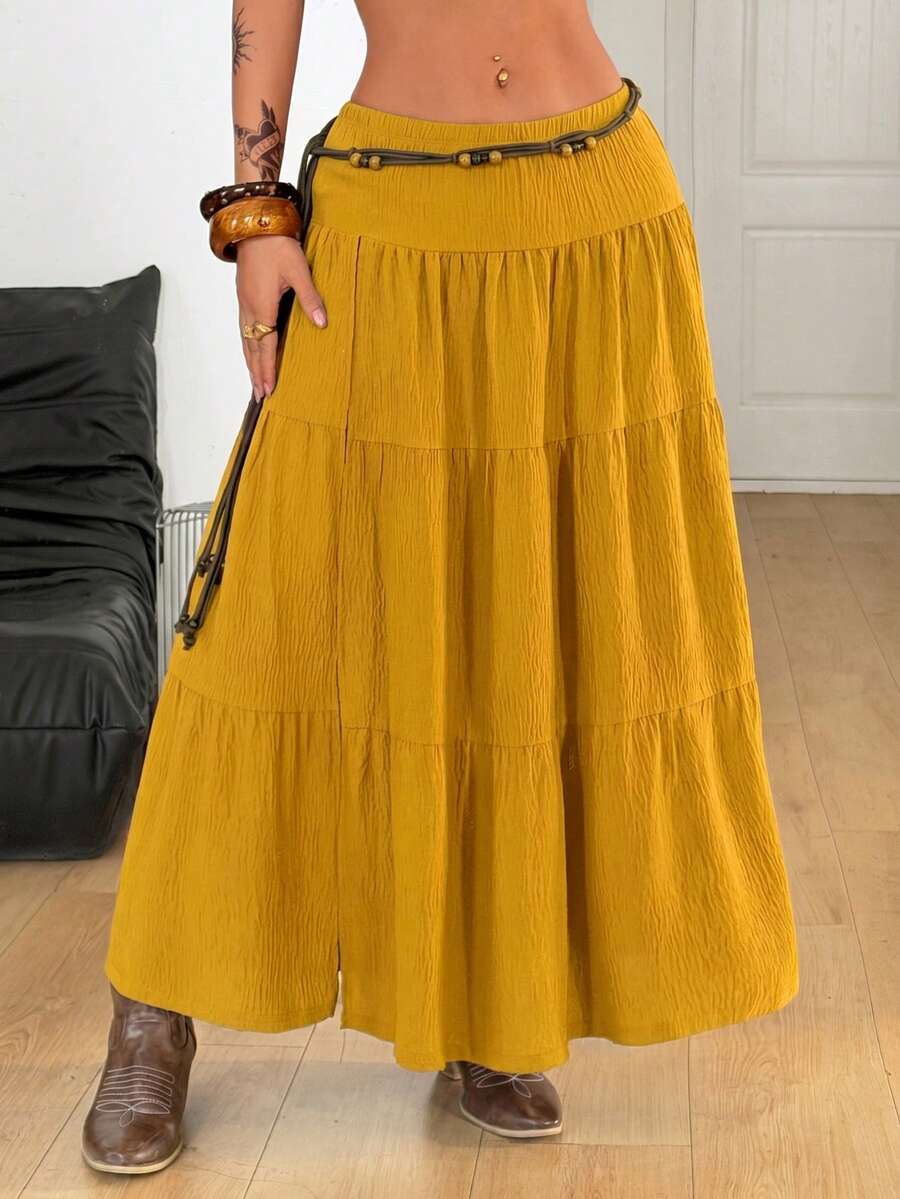 Mustard yellow low waist long skirt with a split thigh design and flared tiered hem in textured woven fabric for women.