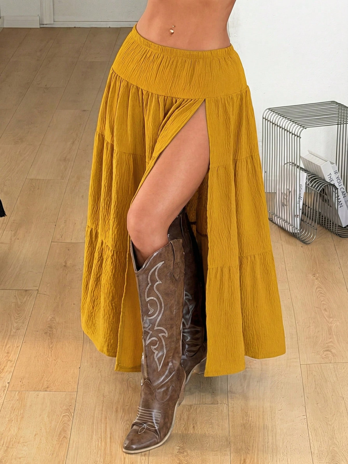 Mustard yellow low waist long skirt with a split thigh design and flared tiered hem in textured woven fabric for women.