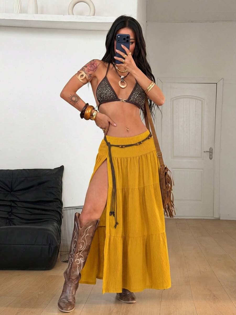Mustard yellow low waist long skirt with a split thigh design and flared tiered hem in textured woven fabric for women.