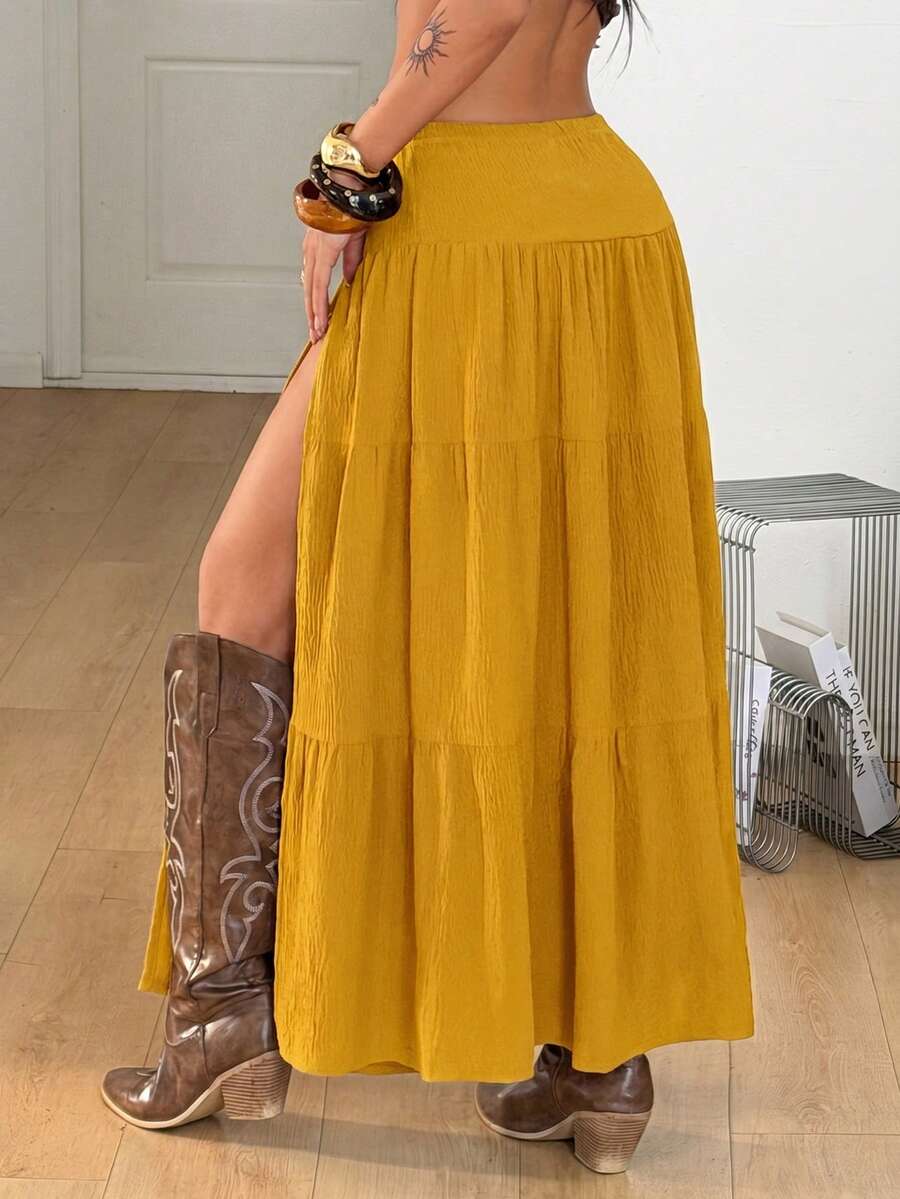 Mustard yellow low waist long skirt with a split thigh design and flared tiered hem in textured woven fabric for women.