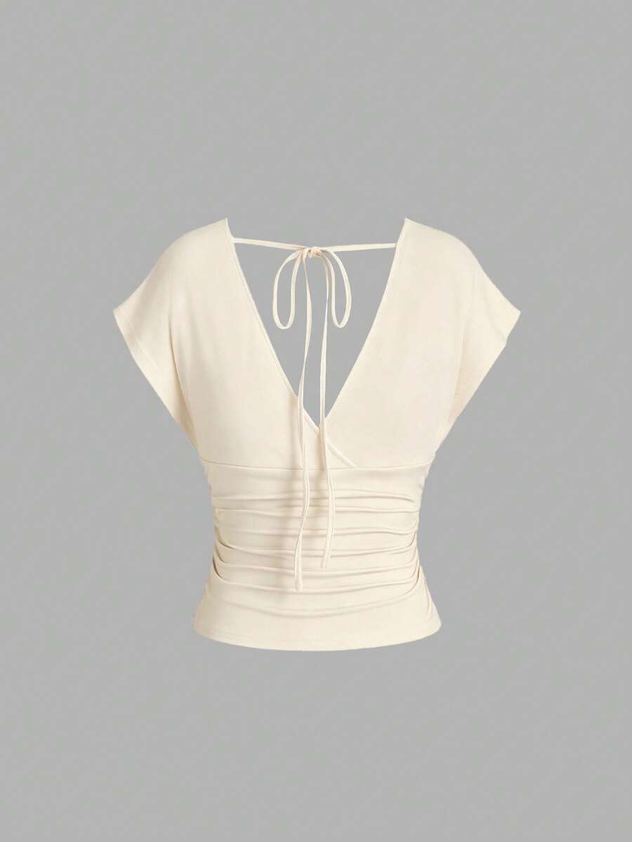 Women's black knitted t-shirt featuring a reversible deep v-neckline, batwing cap sleeves, ruched detailing, and a slim fit waist.