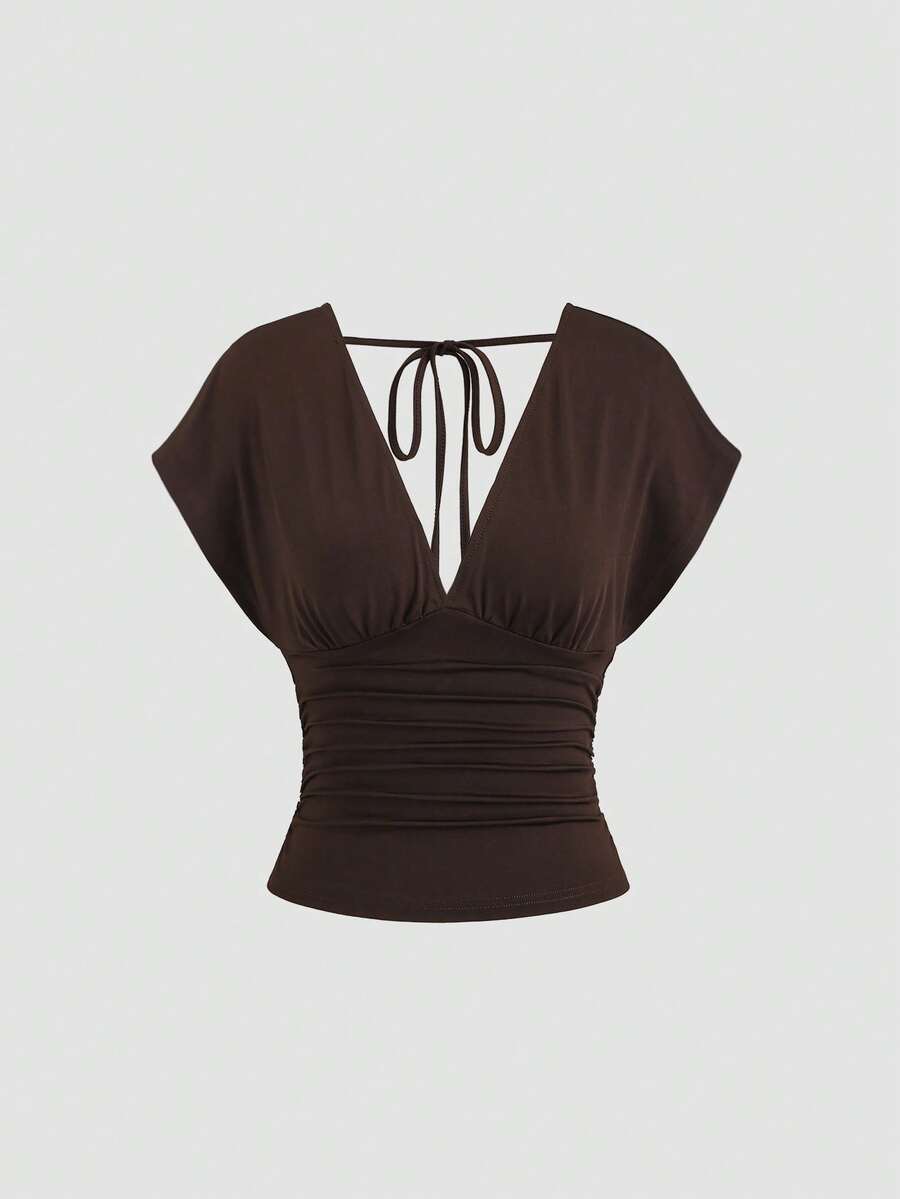 Women's black knitted t-shirt featuring a reversible deep v-neckline, batwing cap sleeves, ruched detailing, and a slim fit waist.