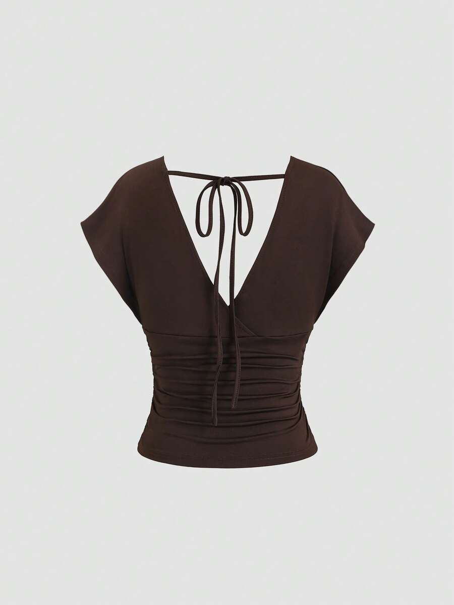 Women's black knitted t-shirt featuring a reversible deep v-neckline, batwing cap sleeves, ruched detailing, and a slim fit waist.