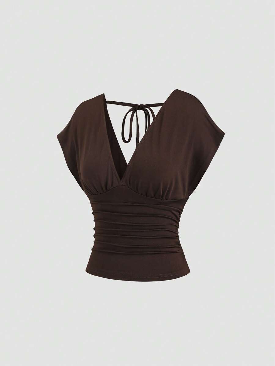Women's black knitted t-shirt featuring a reversible deep v-neckline, batwing cap sleeves, ruched detailing, and a slim fit waist.