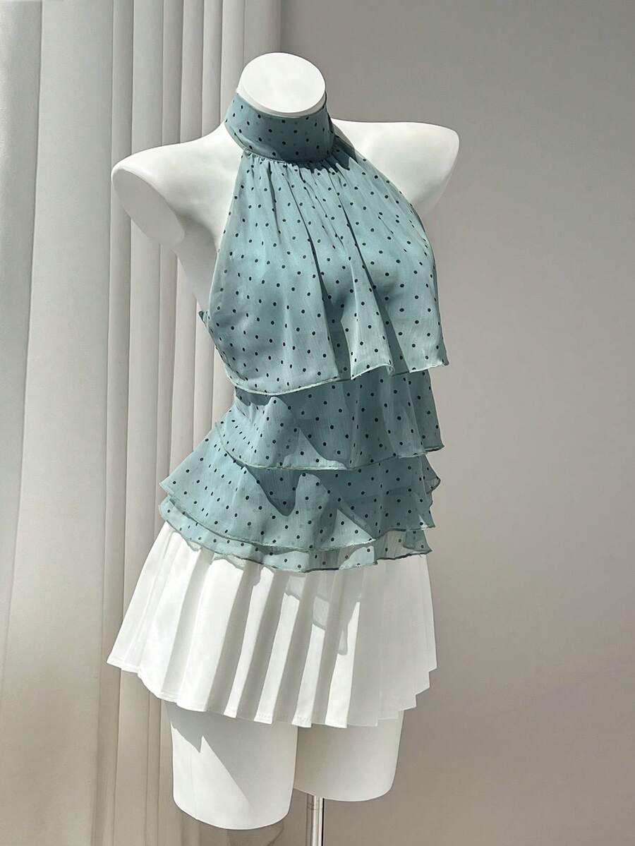 Women's white sleeveless halter neck top featuring pleated fabric, backless tie strap design, and a flared layered ruffle hem.