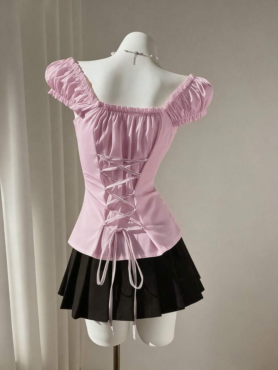 Women's black off-shoulder cap sleeve blouse with ruffled detailing and a tie-back design.