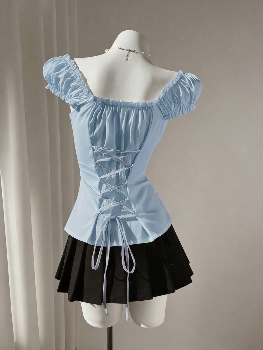 Women's black off-shoulder cap sleeve blouse with ruffled detailing and a tie-back design.