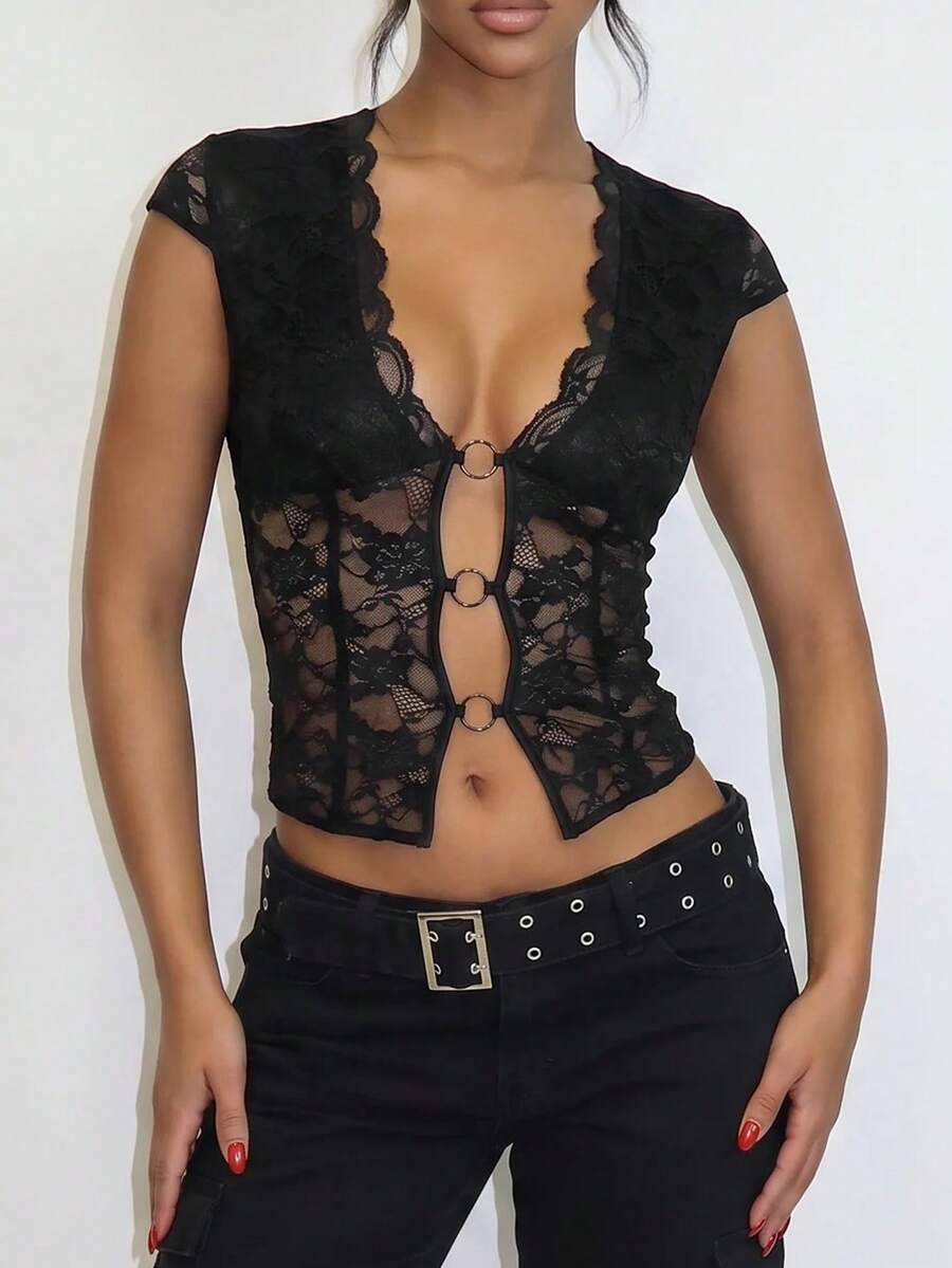 Women's black slim fit semi-sheer blouse featuring contrast lace detailing, a deep V hollow design with ring accent, asymmetrical hem, and cap sleeves.