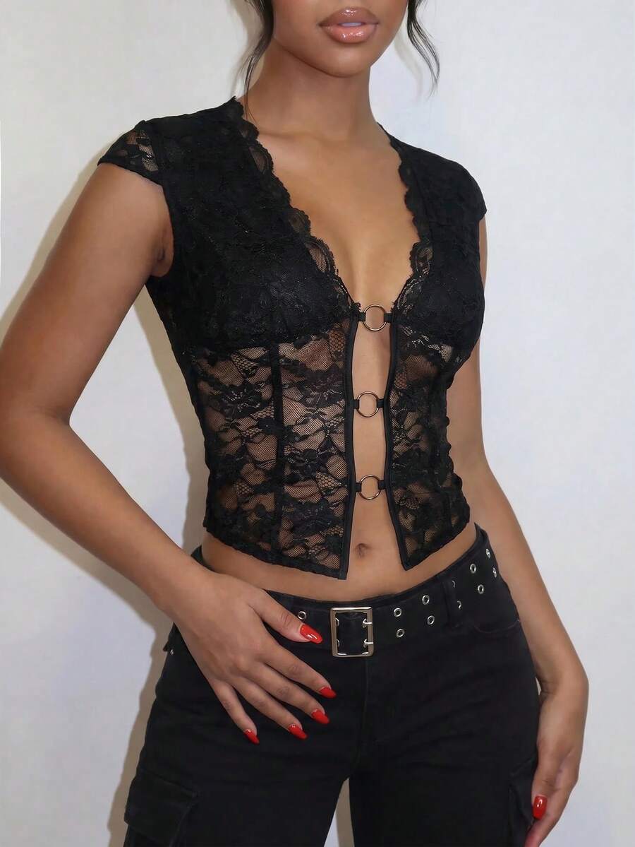 Women's black slim fit semi-sheer blouse featuring contrast lace detailing, a deep V hollow design with ring accent, asymmetrical hem, and cap sleeves.