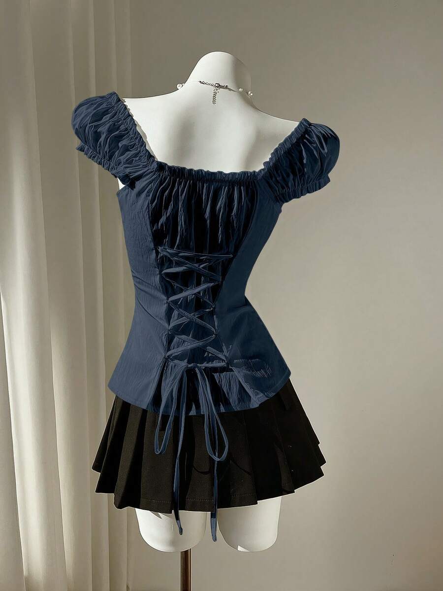 Women's black off-shoulder cap sleeve blouse with ruffled detailing and a tie-back design.