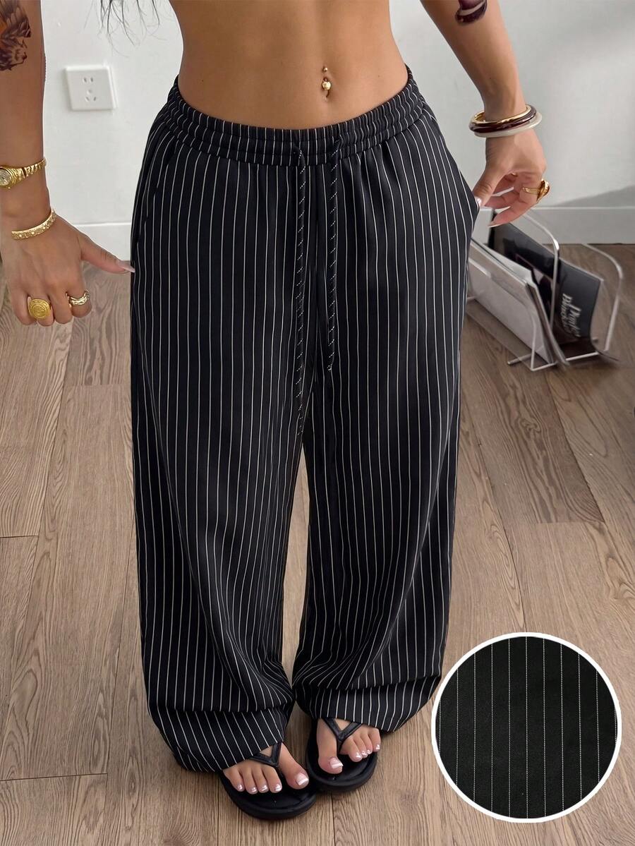 Women's black and white striped wide leg pants featuring an adjustable drawstring waist and side pockets.