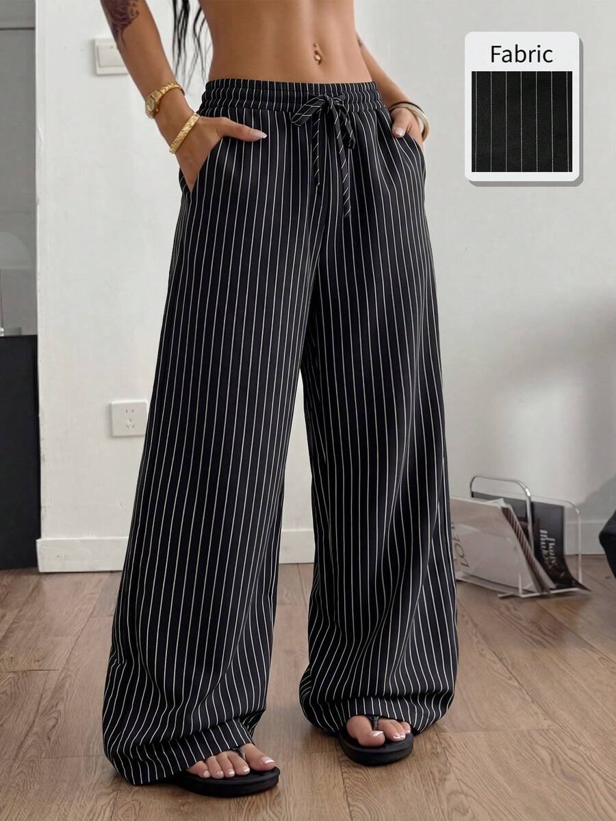 Women's black and white striped wide leg pants featuring an adjustable drawstring waist and side pockets.