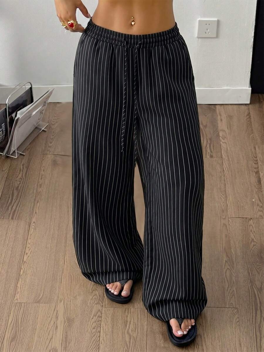 Women's black and white striped wide leg pants featuring an adjustable drawstring waist and side pockets.