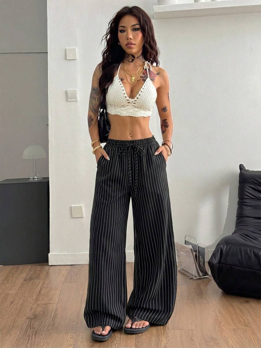 Women's black and white striped wide leg pants featuring an adjustable drawstring waist and side pockets.