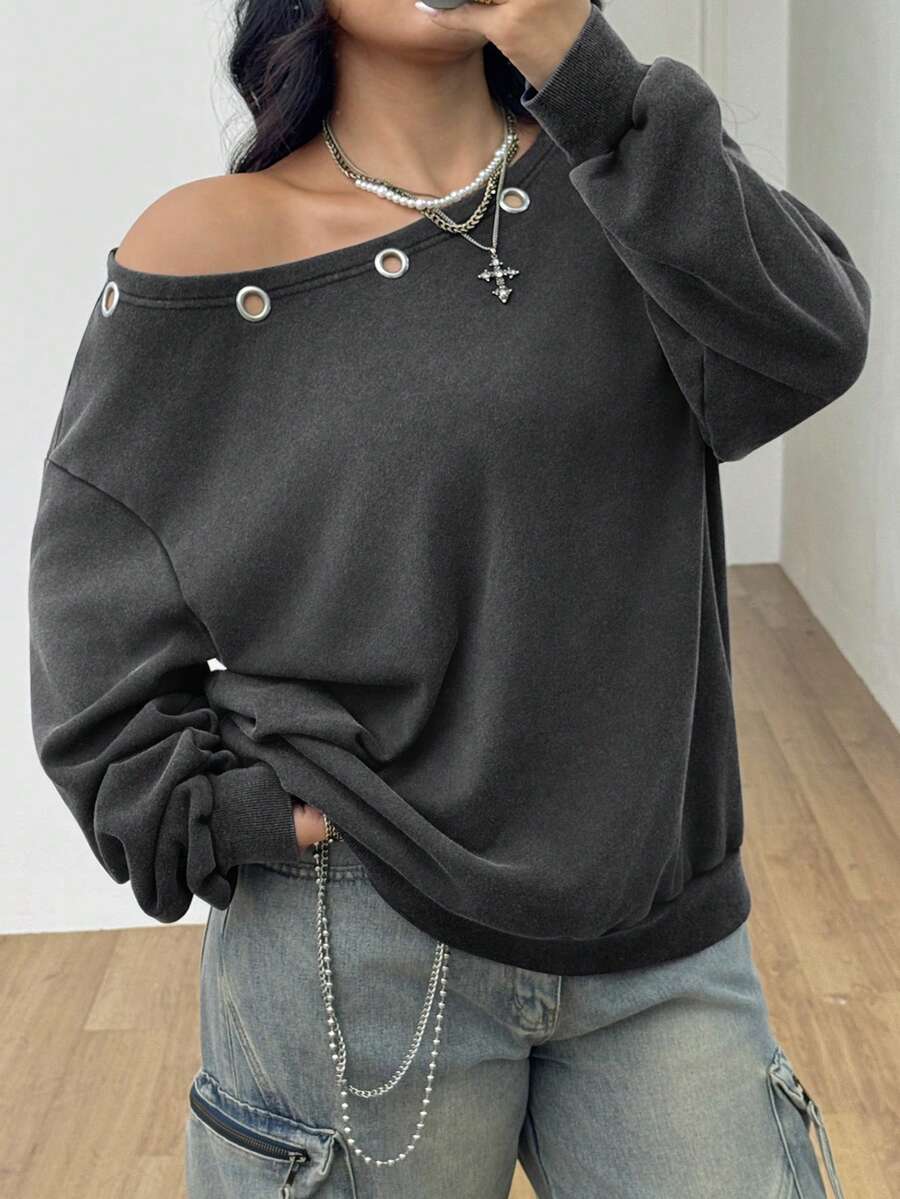 Women's oversized dark grey long sleeve sweatshirt featuring an asymmetrical boat neckline with grommet eyelet details and drop shoulders.
