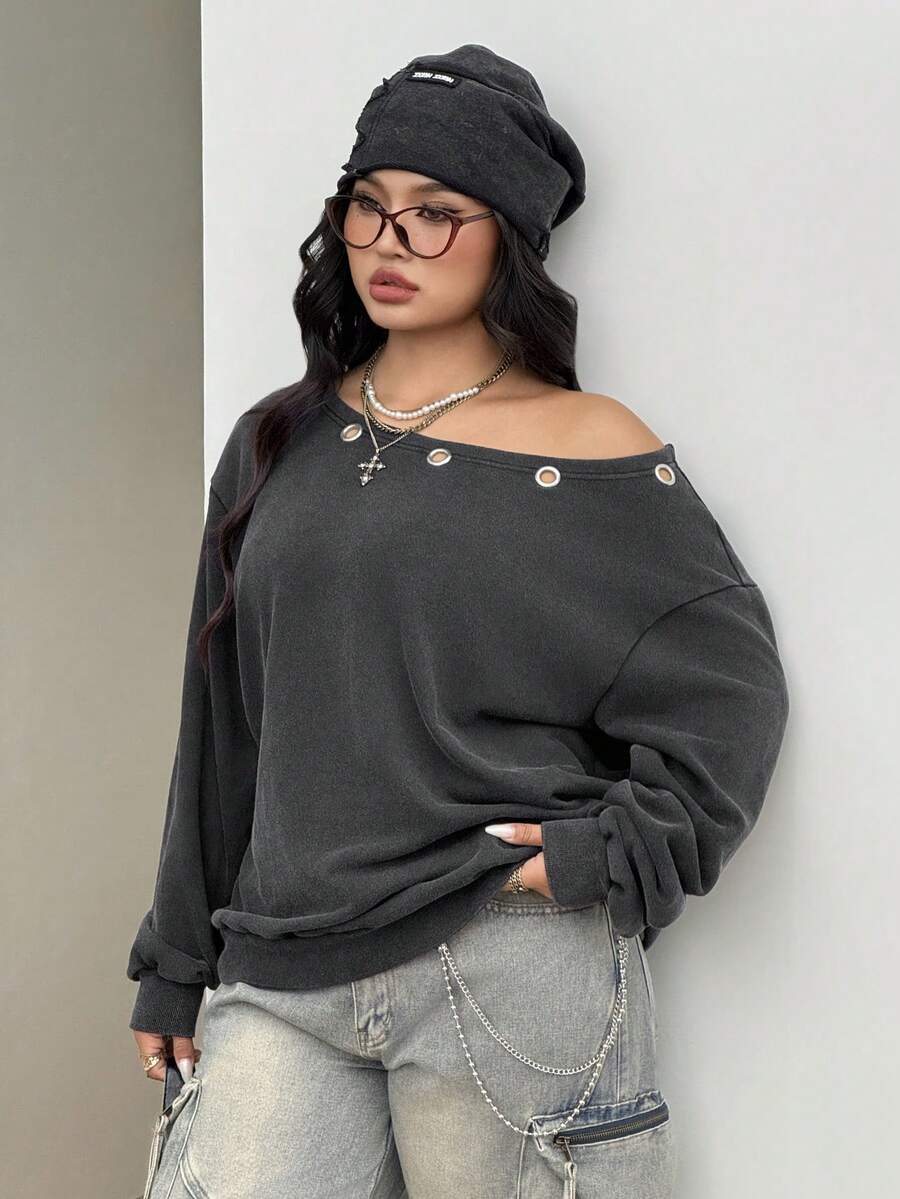 Women's oversized dark grey long sleeve sweatshirt featuring an asymmetrical boat neckline with grommet eyelet details and drop shoulders.