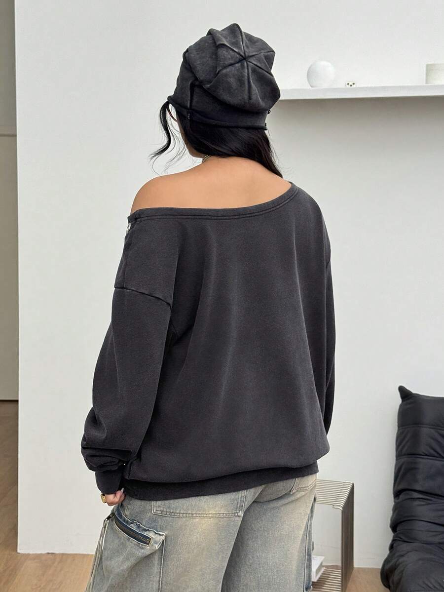 Women's oversized dark grey long sleeve sweatshirt featuring an asymmetrical boat neckline with grommet eyelet details and drop shoulders.