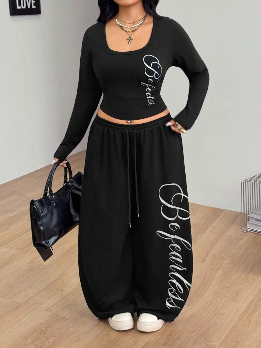 Women's black two-piece casual outfit featuring a long sleeve scoop neck letter print t-shirt and matching wide leg sweatpants made of knitted cotton blend fabric.