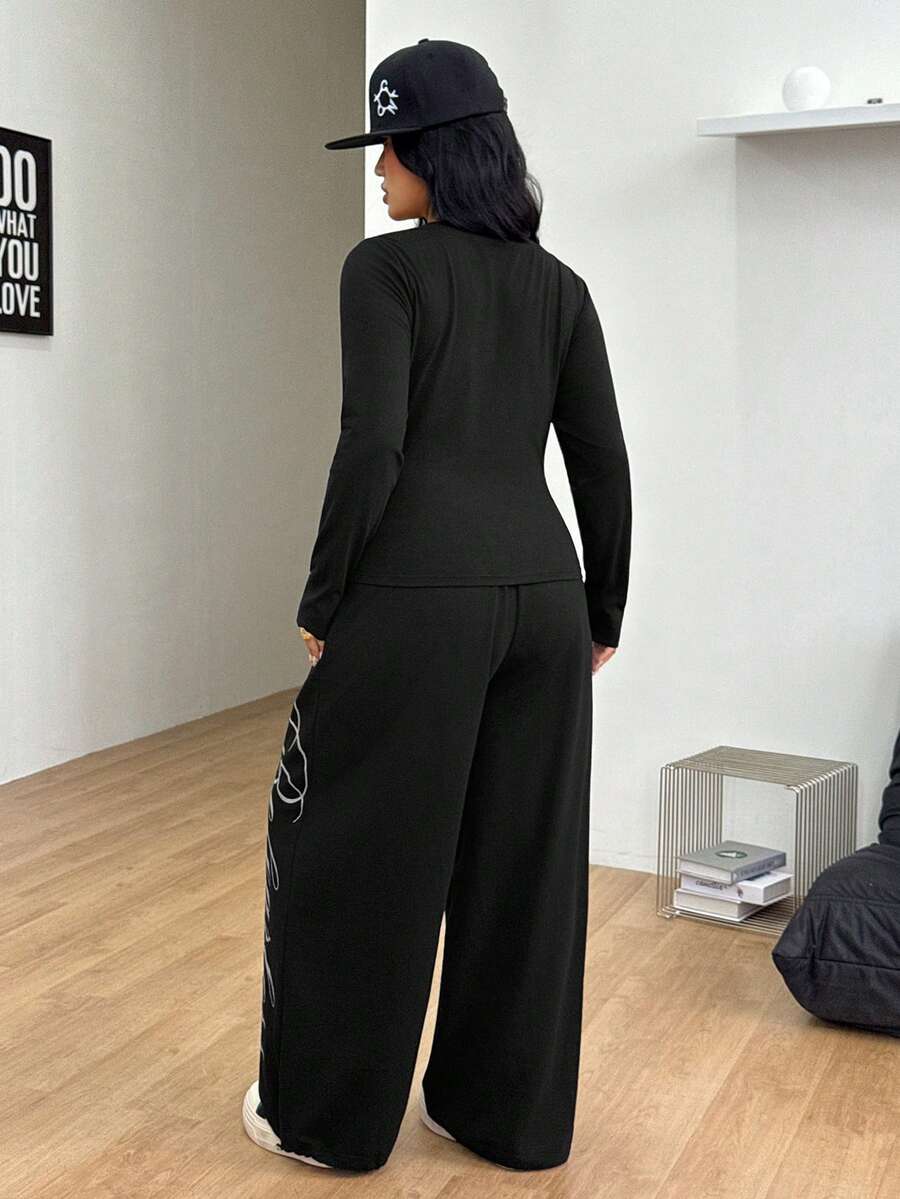 Women's black two-piece casual outfit featuring a long sleeve scoop neck letter print t-shirt and matching wide leg sweatpants made of knitted cotton blend fabric.