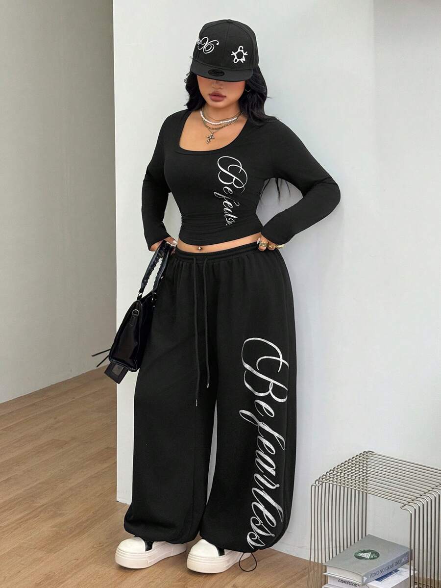 Women's black two-piece casual outfit featuring a long sleeve scoop neck letter print t-shirt and matching wide leg sweatpants made of knitted cotton blend fabric.