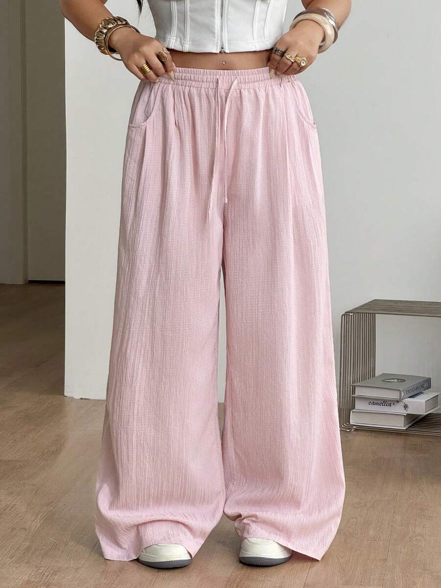 Women's loose straight leg cotton pants featuring a high waist with an adjustable drawstring knot and functional side pockets.
