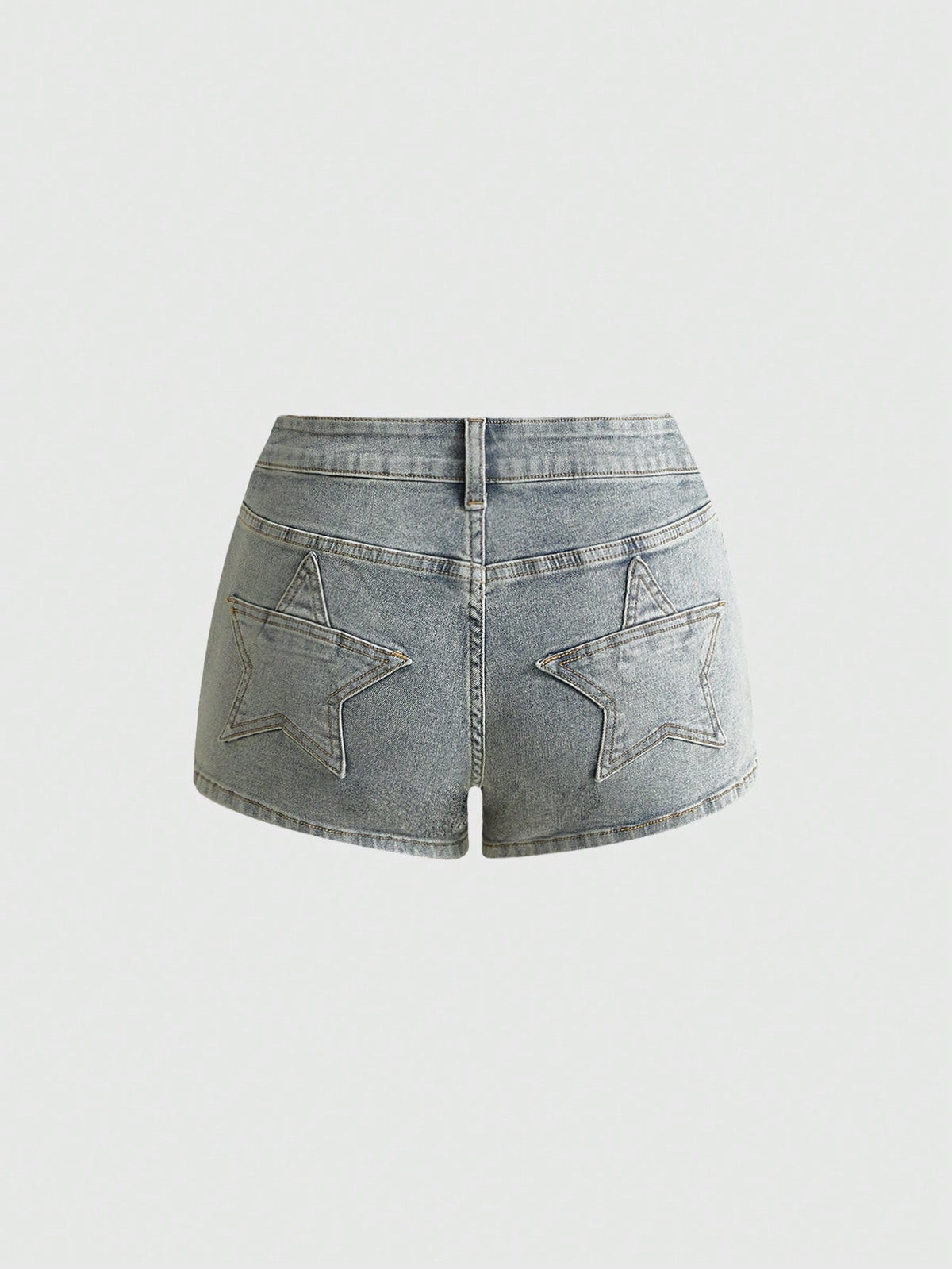 Women's ultra low waist mini shorts with back pockets, zipper fly, button detail, random print, and star patch in a grunge punk Y2K style.
