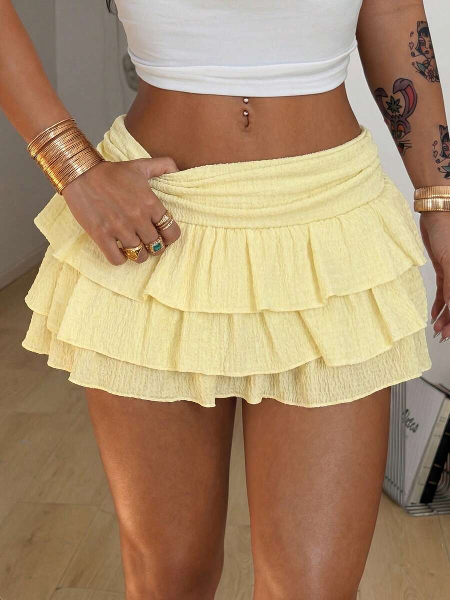 Women's white low waist tiered mini skirt featuring ruched detailing and a slight-stretch knitted fabric.