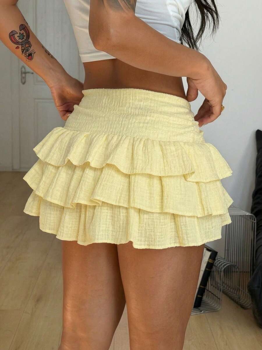 Women's white low waist tiered mini skirt featuring ruched detailing and a slight-stretch knitted fabric.