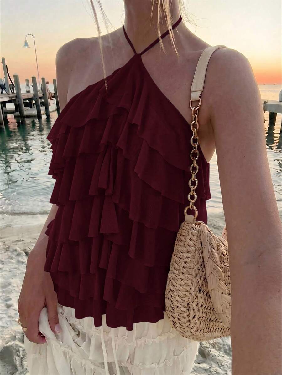 Women's sleeveless halter neck top featuring tiered ruffle layers, a backless cut, and an asymmetrical hem.