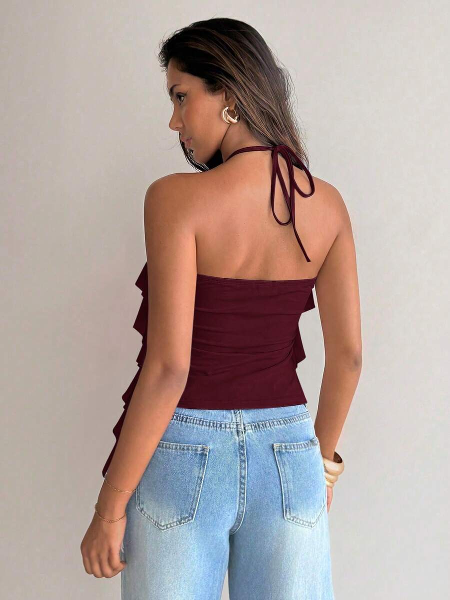 Women's sleeveless halter neck top featuring tiered ruffle layers, a backless cut, and an asymmetrical hem.