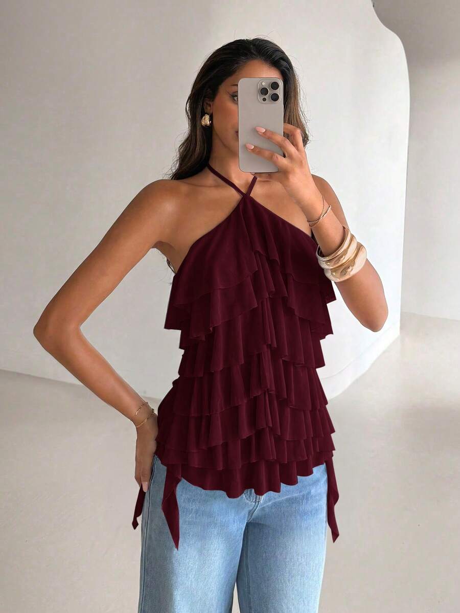 Women's sleeveless halter neck top featuring tiered ruffle layers, a backless cut, and an asymmetrical hem.