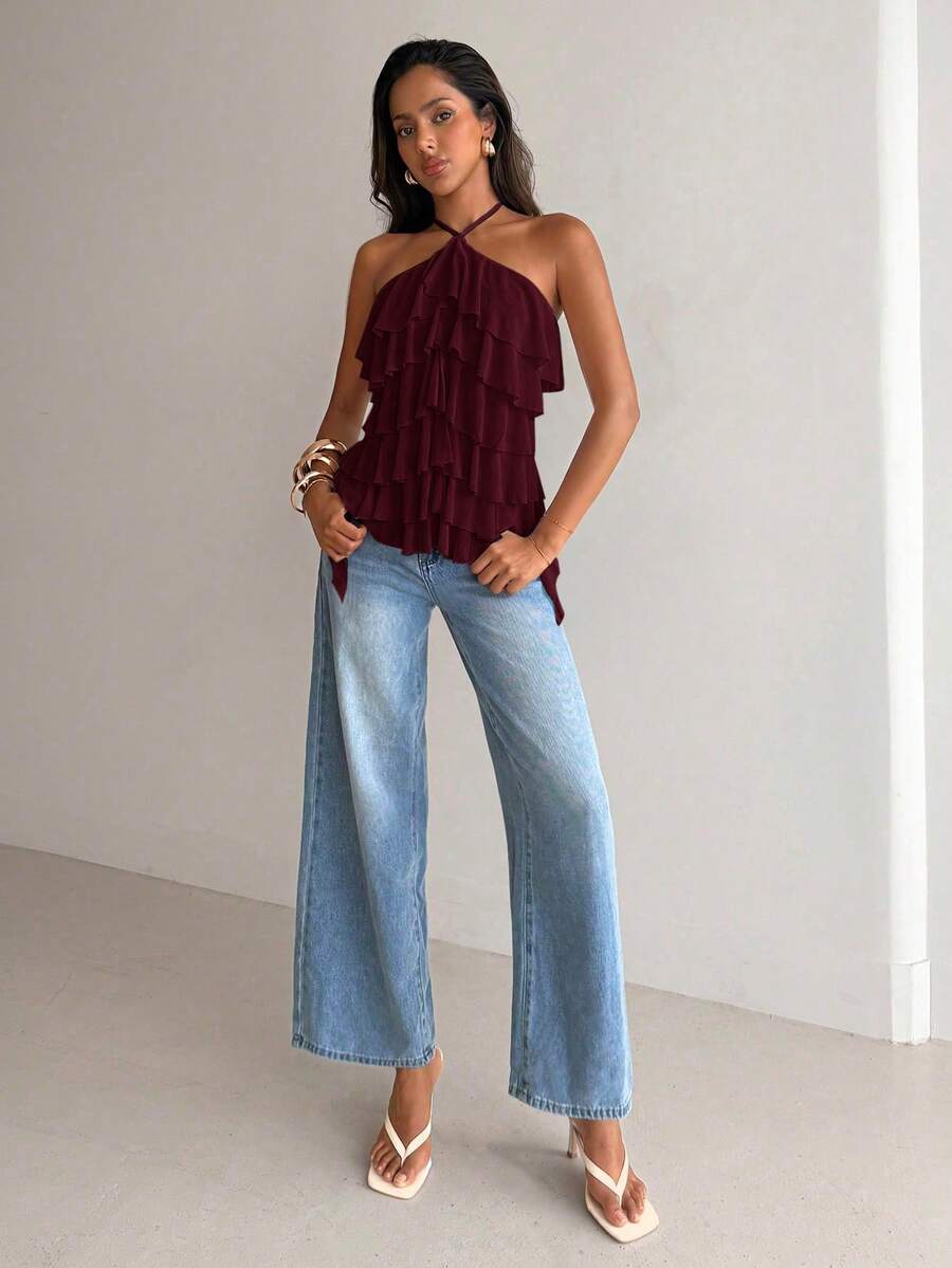 Women's sleeveless halter neck top featuring tiered ruffle layers, a backless cut, and an asymmetrical hem.