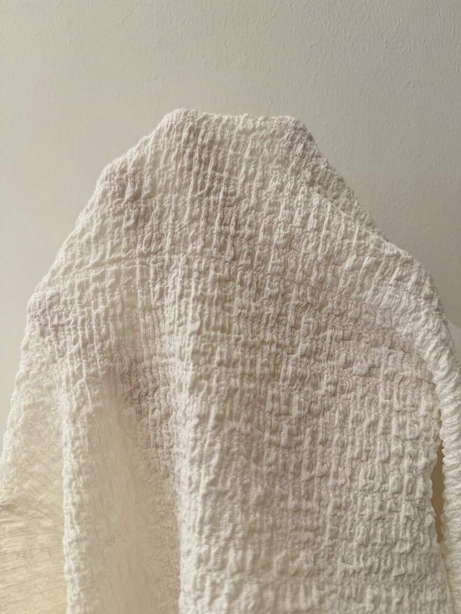 Women's slim fit long sleeve knit top featuring an asymmetrical neckline and grommet eyelet detail