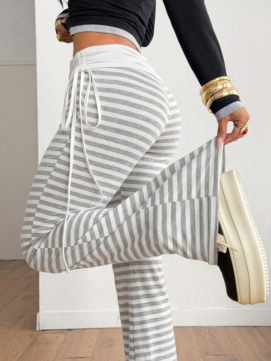 Women's striped flare leg pants featuring a mid-rise waist, slim fit thigh, and ruched side drawstring detail in stretch knit fabric.
