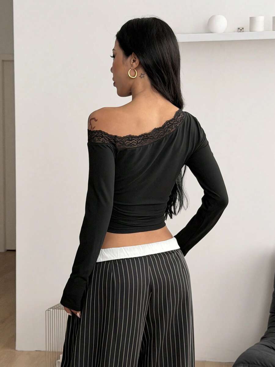 Women's slim fit long sleeve knit top featuring an asymmetrical neckline and grommet eyelet detail