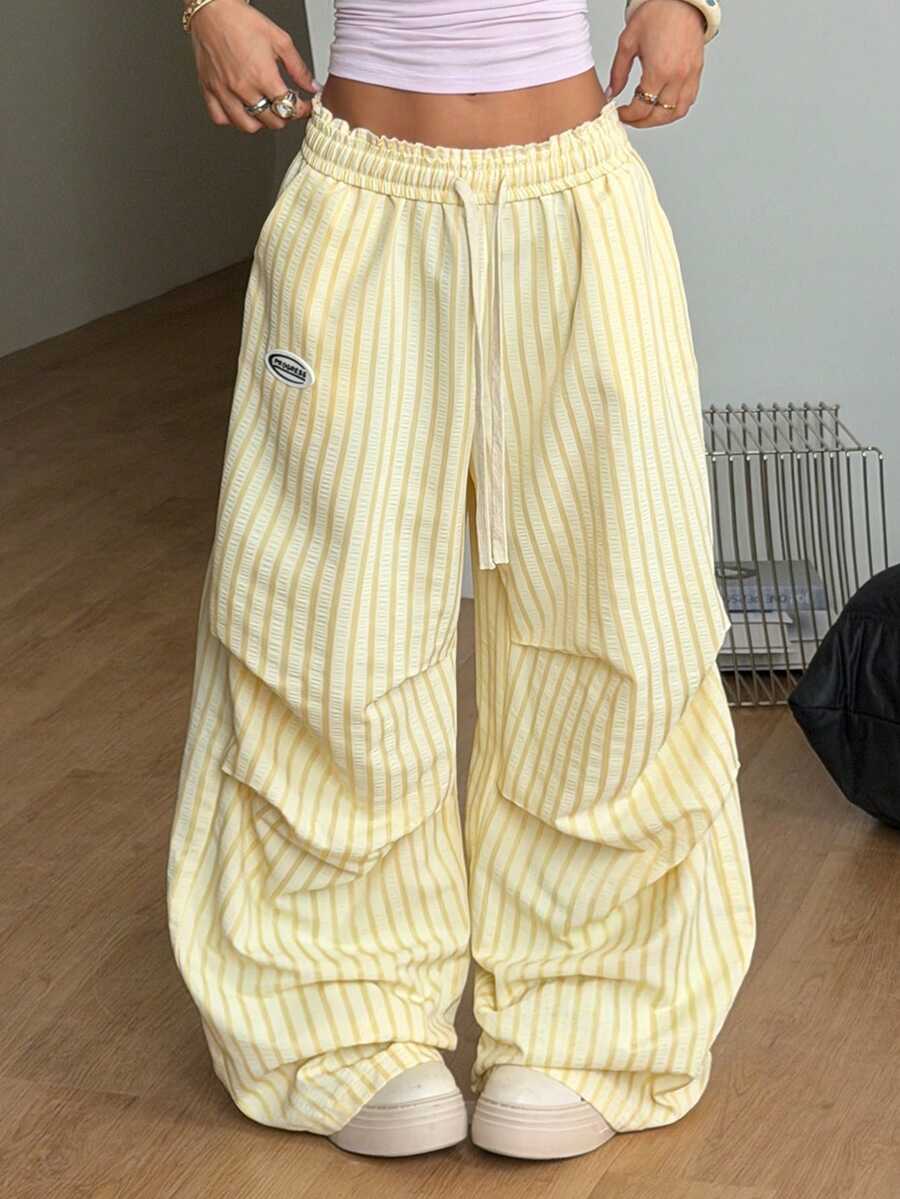 Women's black and white striped wide leg pants featuring an elastic drawstring waistband, side pockets, and a loose straight leg fit.