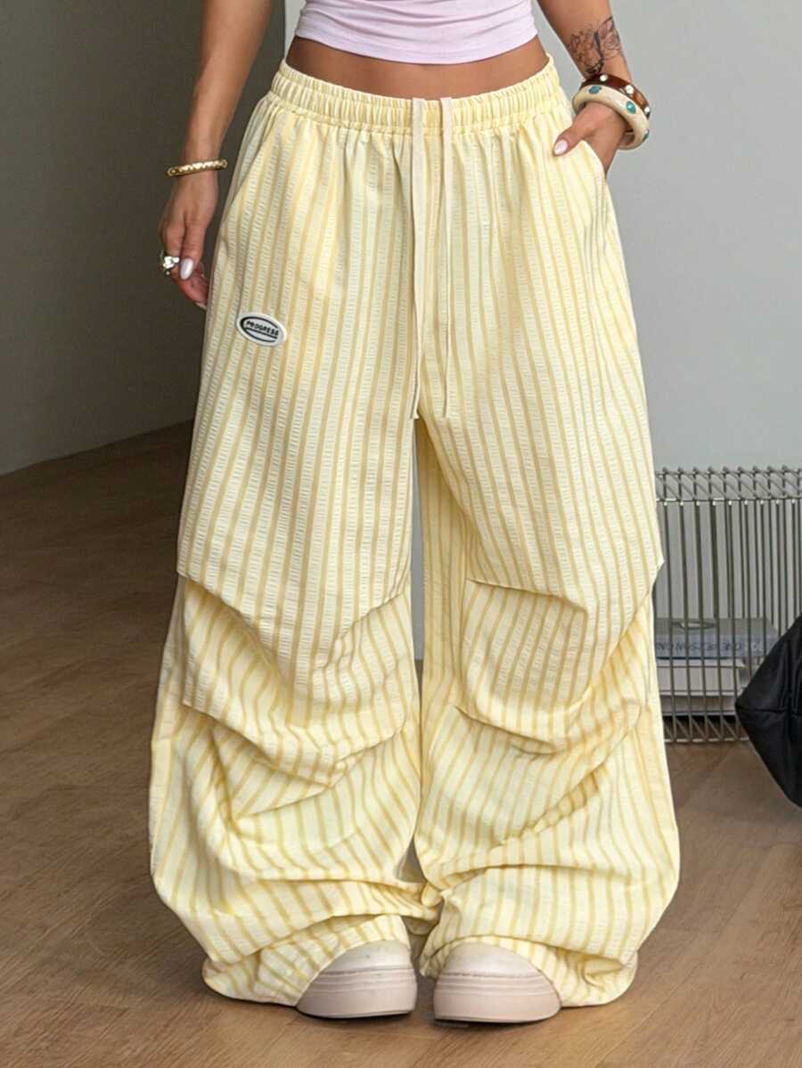 Women's black and white striped wide leg pants featuring an elastic drawstring waistband, side pockets, and a loose straight leg fit.