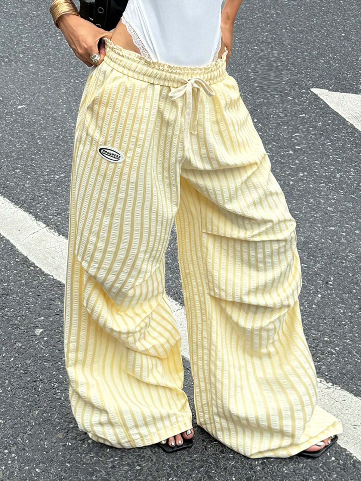 Women's black and white striped wide leg pants featuring an elastic drawstring waistband, side pockets, and a loose straight leg fit.