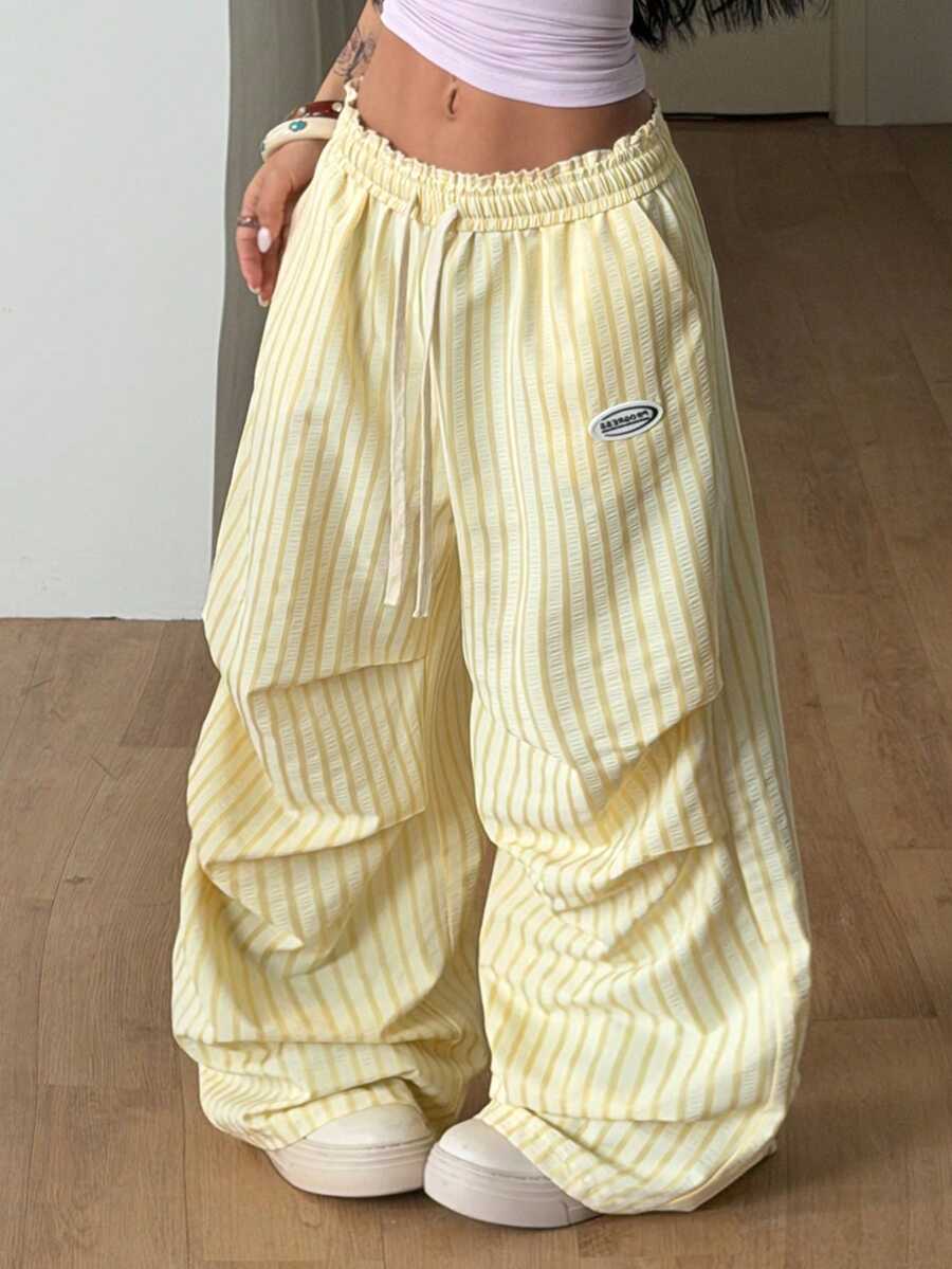 Women's black and white striped wide leg pants featuring an elastic drawstring waistband, side pockets, and a loose straight leg fit.
