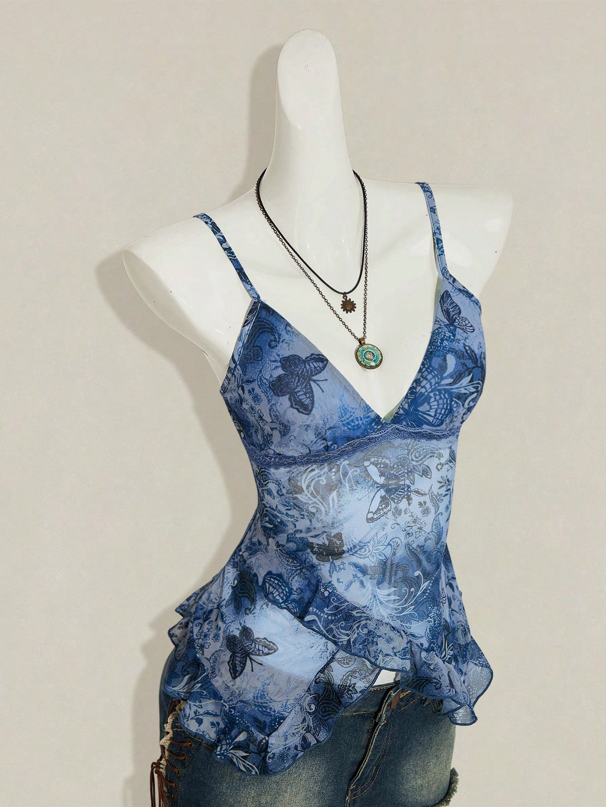Women's graphic print camisole top featuring thin spaghetti straps, a backless cut, and an asymmetrical hem.