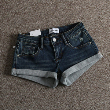 Women's low-waist shorts with ripped hem, asymmetrical detail, straight-leg cut, and pockets.