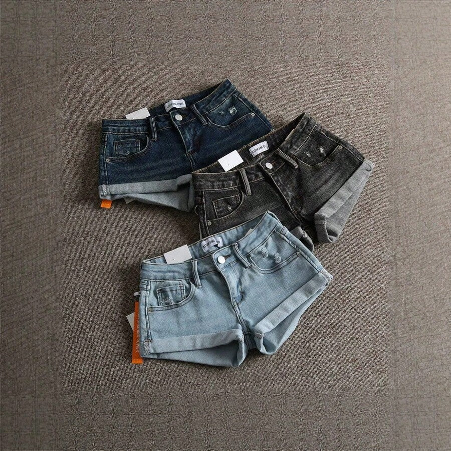 Women's low-waist shorts with ripped hem, asymmetrical detail, straight-leg cut, and pockets.