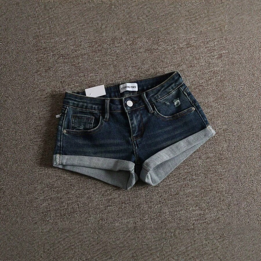 Women's low-waist shorts with ripped hem, asymmetrical detail, straight-leg cut, and pockets.