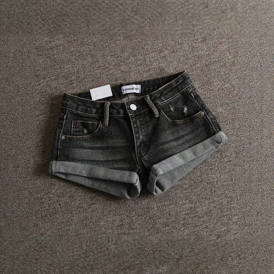 Women's low-waist shorts with ripped hem, asymmetrical detail, straight-leg cut, and pockets.